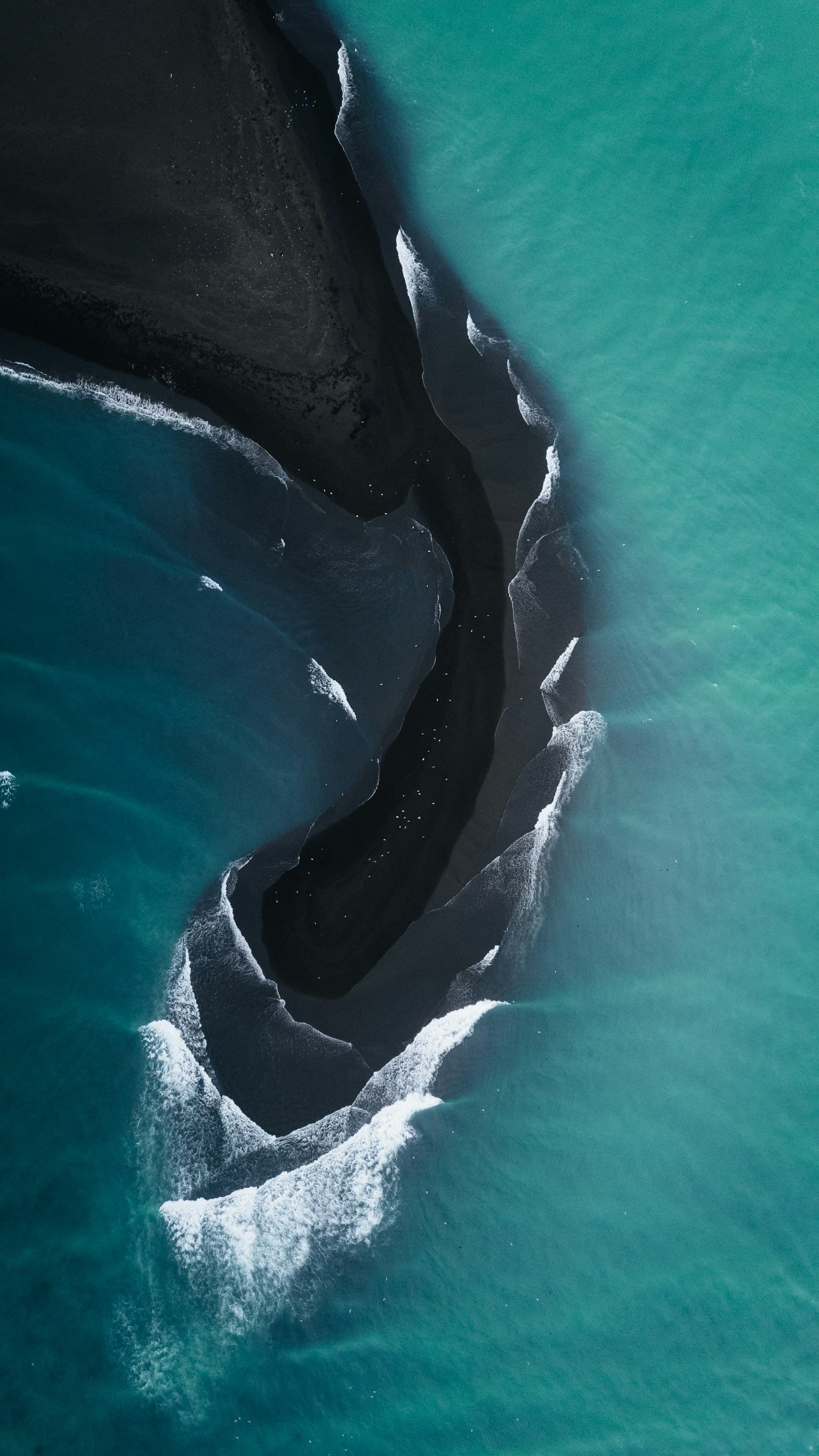 Waves writing and erasing lines along a black-sand shore in Iceland