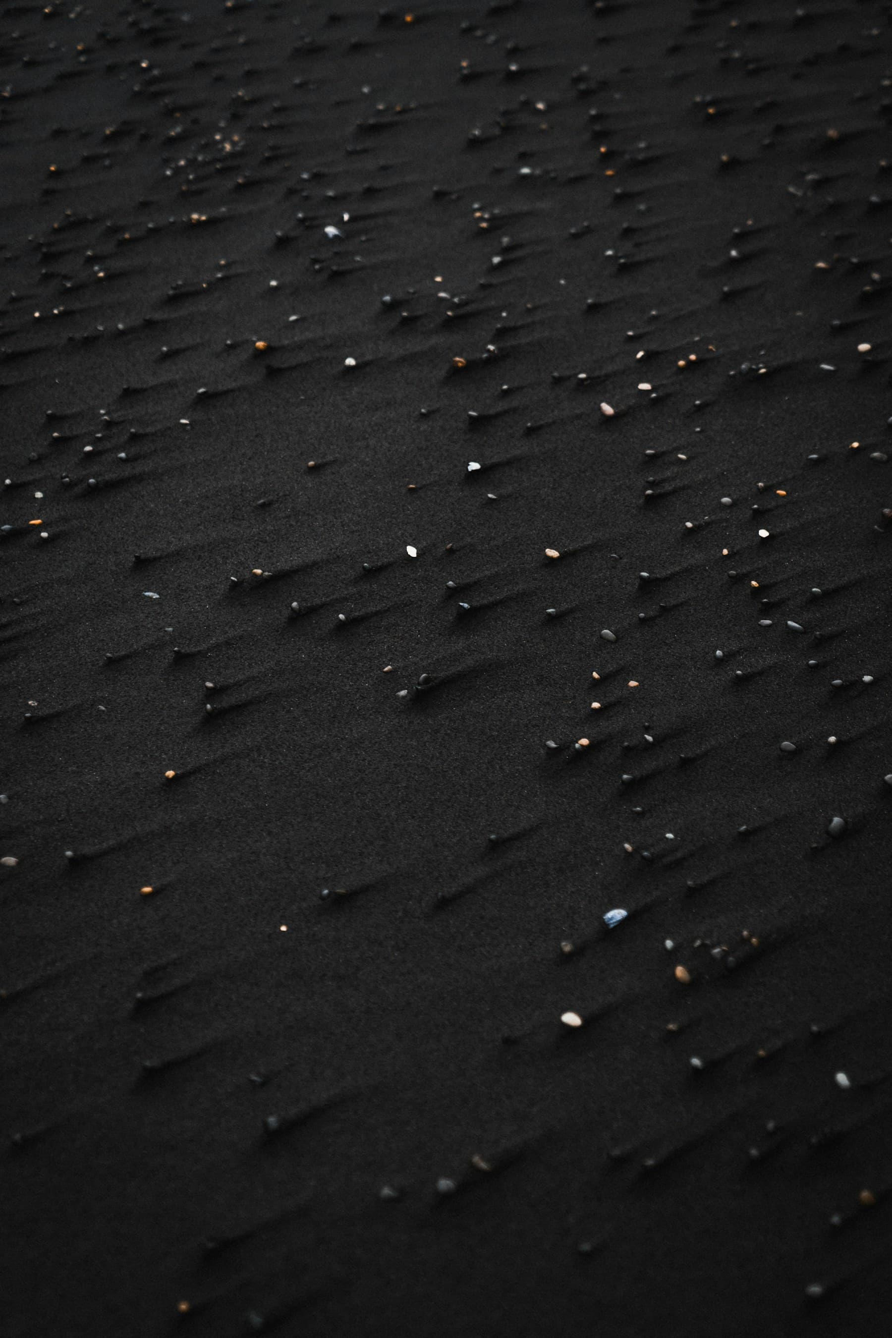 Small stones and wind lines remaining visible in black sand